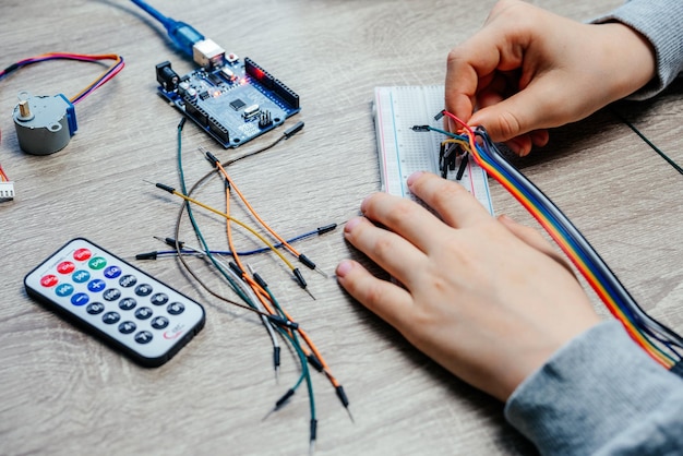 A child plugging cables to sensor chips while learning arduino coding and robotics