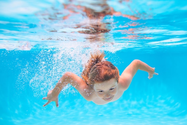 Child in pool in summer day child swimming underwater in swimming pool funny kids boy play and swim