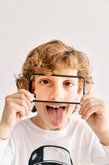 Child posing sticking tongue with his mobile phone and photos made of parts of his face