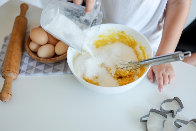 The child pours sugar into the dough cooking