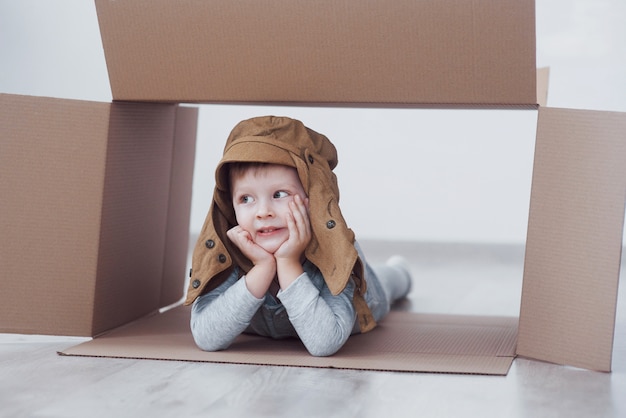 Child preschooler boy playing inside paper box. Childhood, repairs and new house 