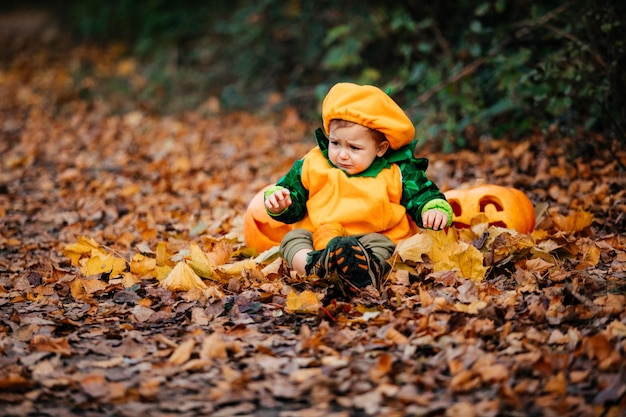 Child in pumpkin costume exploring park at Helloween