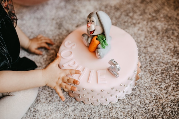 Child reaching for a cake with marzipan decorations and a candle