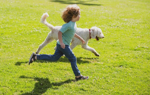 Child runnin with a dog in park kid with a puppy dog outdoor playing at backyard lawn