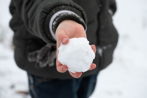 Photo a child's hand holding a round snowball.