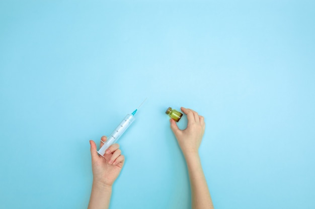 A child's hand holds a syringe