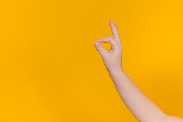 The child's hand makes a OK on a yellow isolated