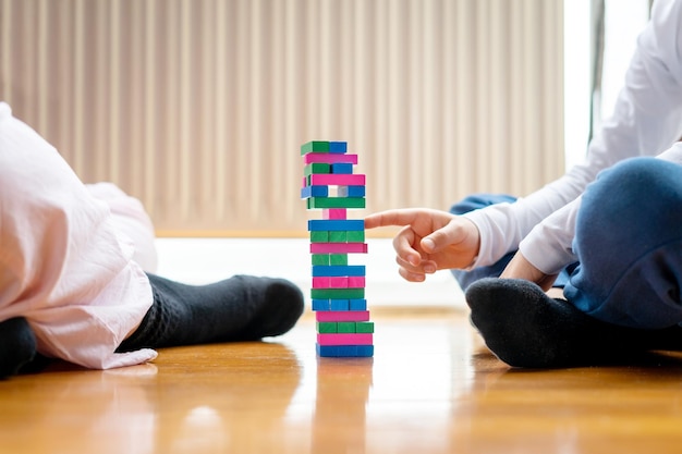 Child's hand playing with his mother with wooden blocks trying not to knock them down