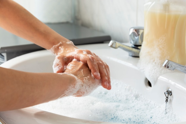 Child's hand wash his hands over sink in bathroom.