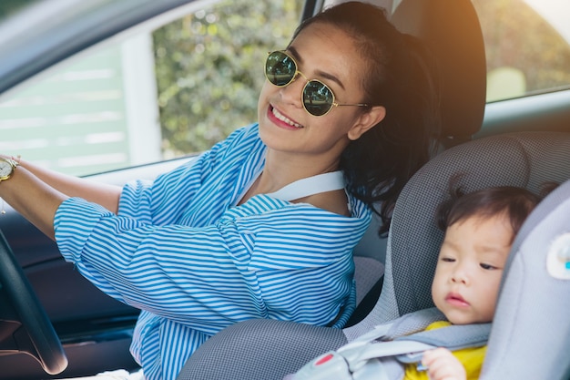  child in a safety seat near to mother who sits on forward sitting of the car. Car insuran