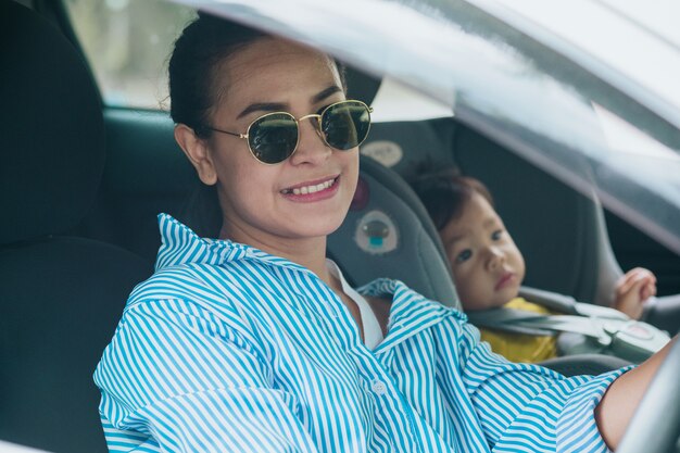 Child in a safety seat near to mother who sits on forward sitting of the car