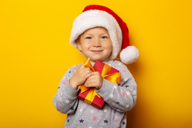 Child in a Santa Claus hat holds a gift