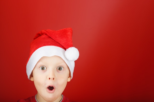 Child in a Santa hat looks out in surprise from the bottom of the frame