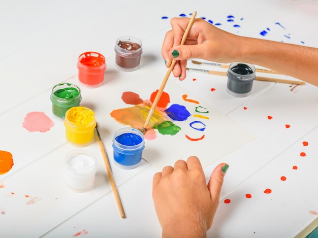 The child selects the desired color on a white wooden table.