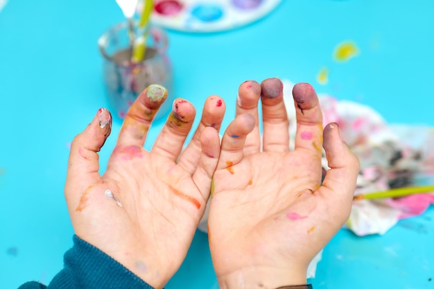 Child showing his dirty hands after painting with watercolors no faces are shown