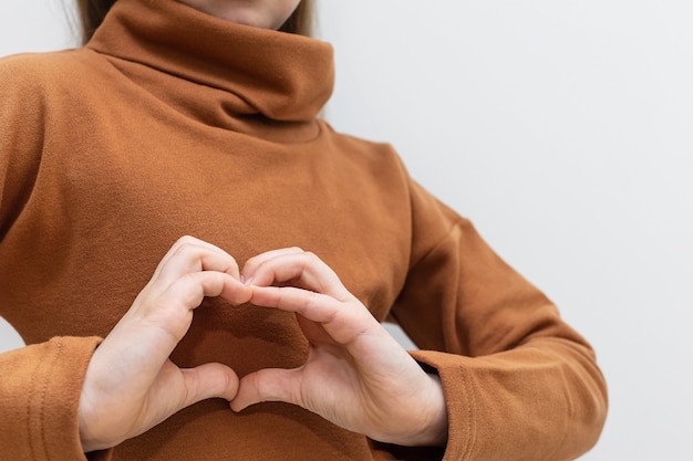 The child shows the heart with his hands in closeup