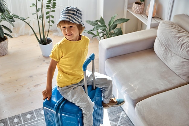 A child sitting on a suitcase have fun and laughs waiting for a trip on vacation