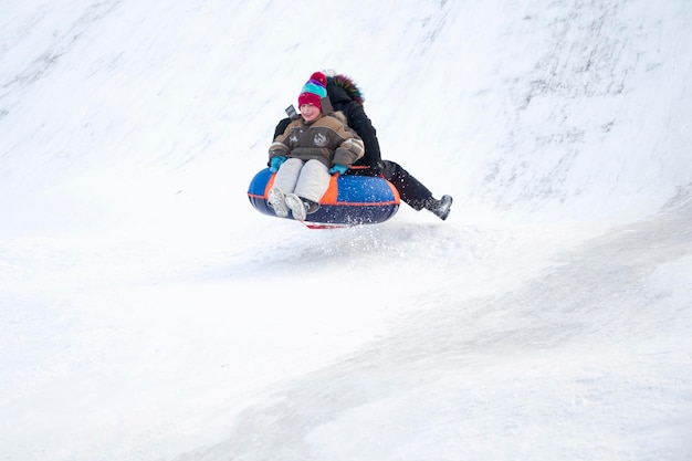 Child sledding cheesecake.Sledding off a snow slide.Ski jumping on tubing. Winter children's holiday