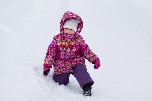 Child standing up from snowdrift in snowy park in winter