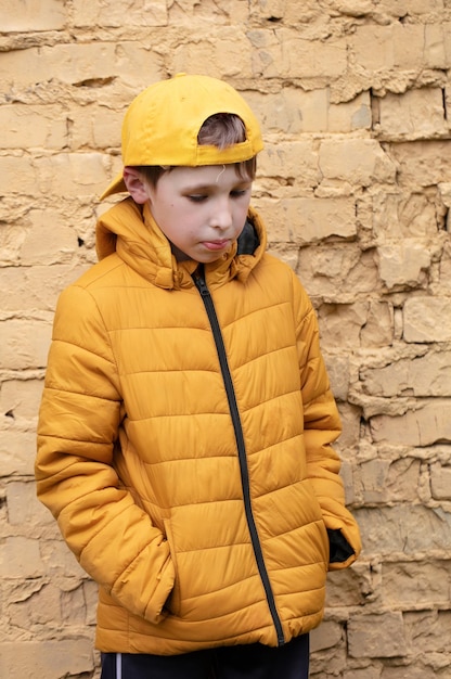 A child on the street A overweight boy is standing against a brick wall in yellow clothes