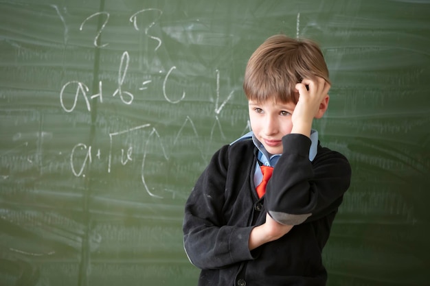 Child student in the classroom The student at the green board is solving a difficult problem