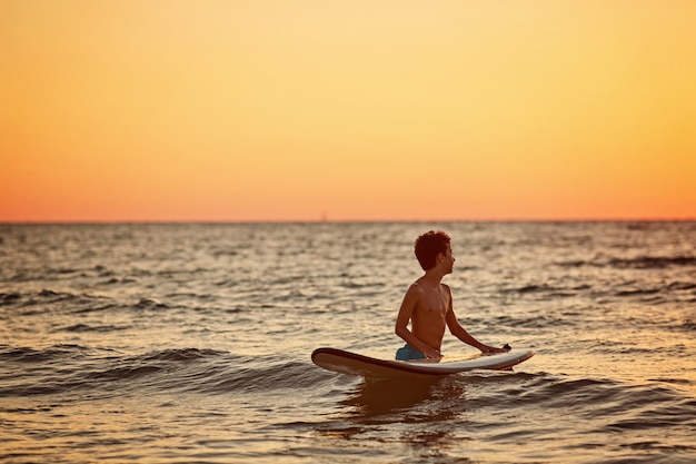 Child surfing on tropical beach. summer vacation in Asia. Kids swim in ocean water