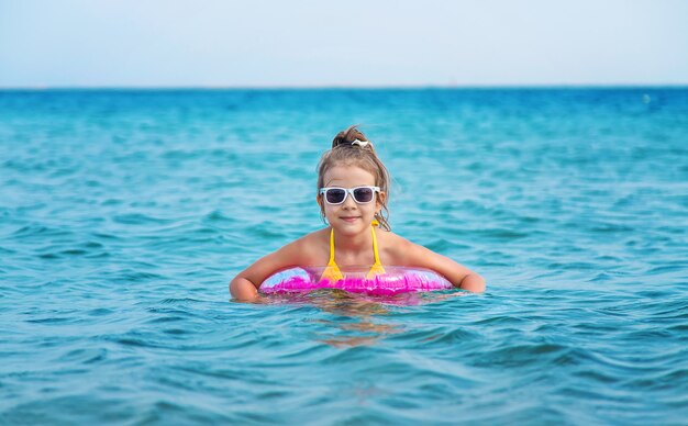 The child swims in a rubber ring in the sea