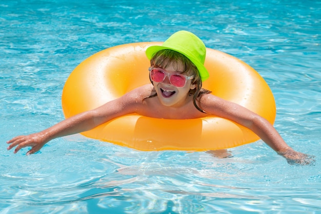 Child swin in swimming pool on inflatable ring Kid swim with orange float Water toy healthy outdoor sport activity for children Fashion summer kids in hat sunglasses