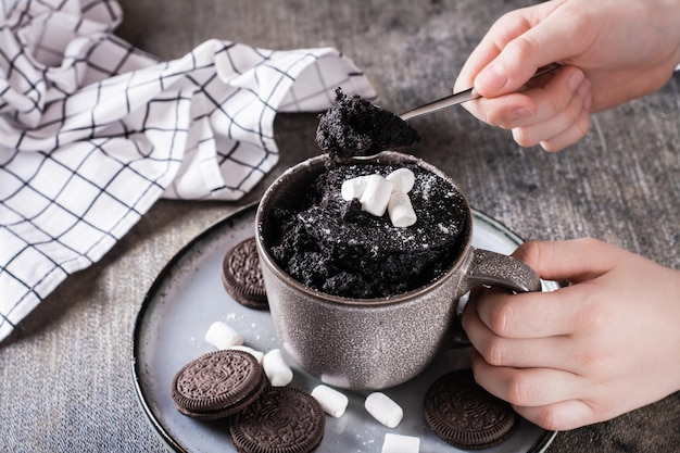 The child takes a spoon chocolate cake mug for dessert