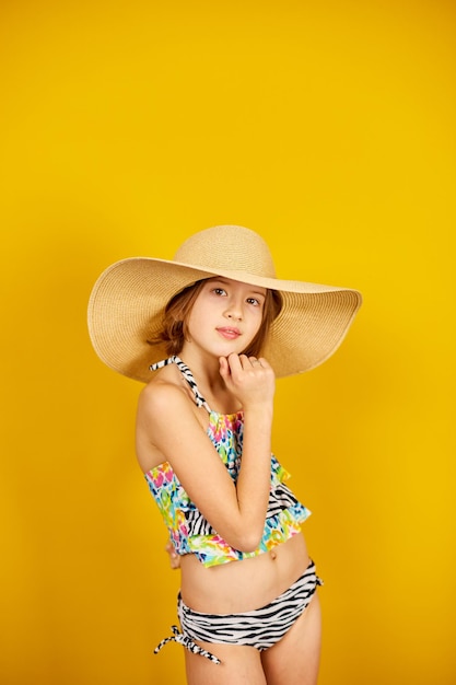 Child teenager girl in swimsuit and straw hat posing