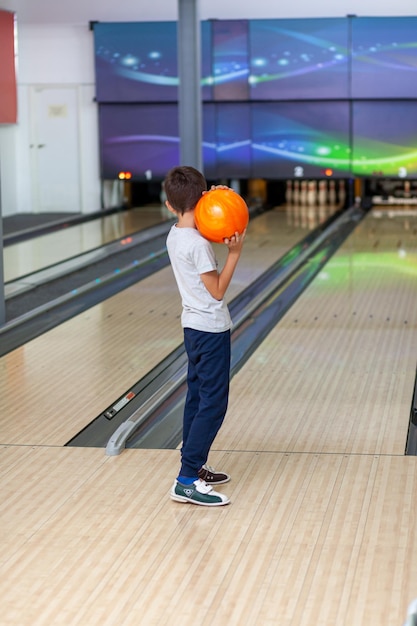 A child throws a ball into a bowling alley. Paths with balls and pins for bowling. A fun game