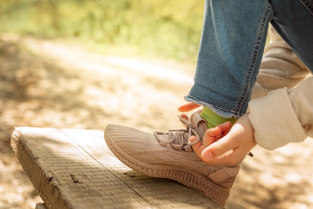 Child tying up laces his sneakers in spring park