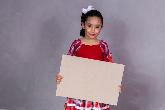 Child in typical clothes of famous Brazilian party called Festa Junina in celebration of Sao Joao Beautiful girl on yellow background Holding a banner with copy space