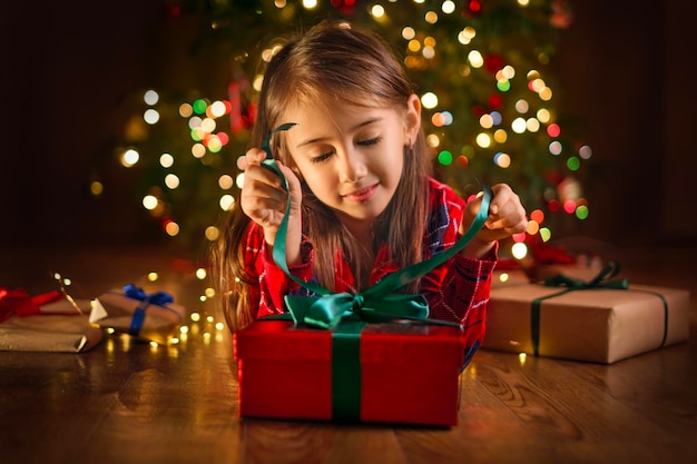 A child unties ribbon on gift box on Christmas night