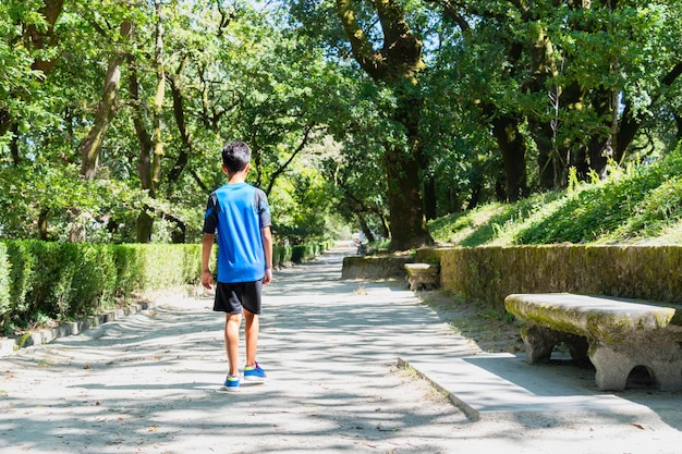 Child walking alone in a city park on a very sunny day.