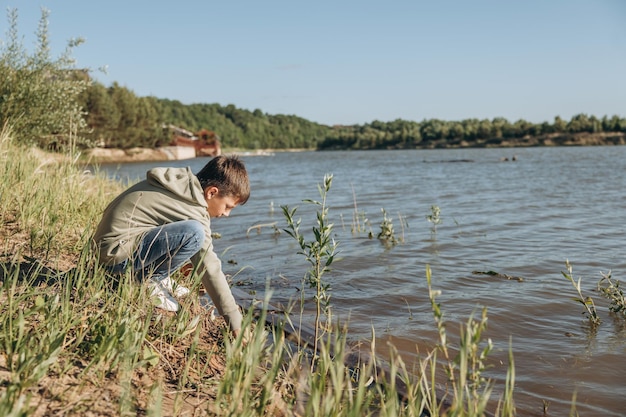 Child walking along river bank Recreation of teenage boy in nature by water