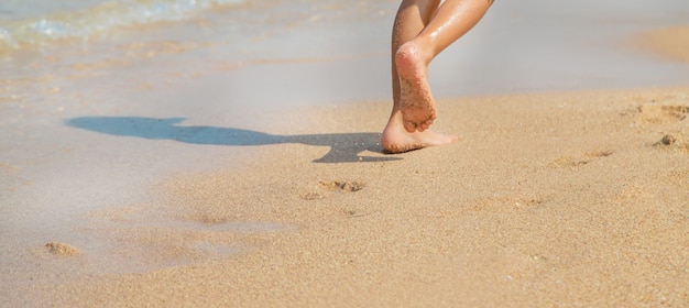 Child walks along the beach leaving footprints in the sand. 