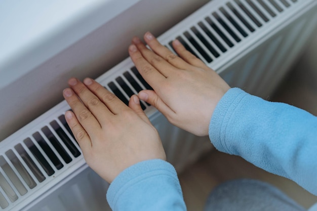 Child warming hands over heater Energy crisis in Europe