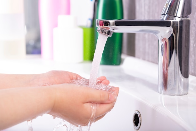 Child washes hands with soap under the tap with water