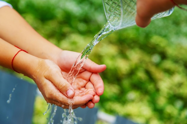 The child washes his hands in the street. Selective focus.