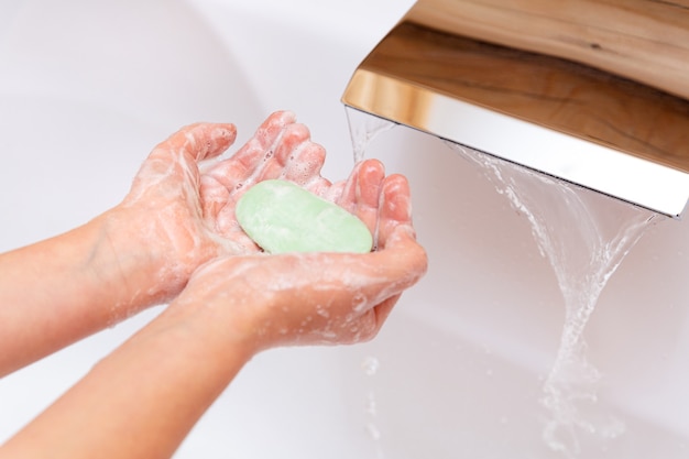 The child washes his hands with soap under a tap with clean water 