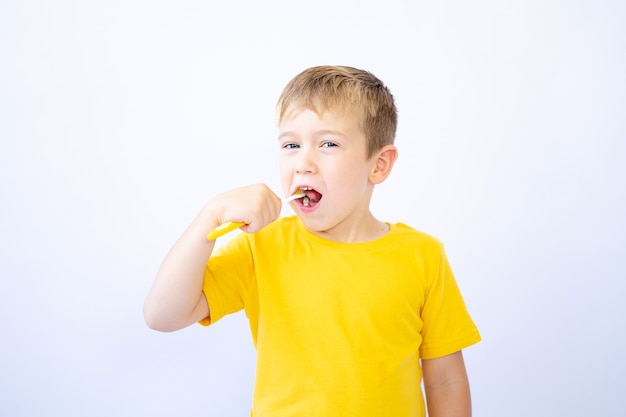 a child on a white background is brushing his teeth holding a toothbrush in his hands isolate