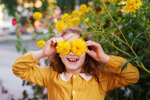 Child with flowers eyes showing white teeth, in a summer outdoors.