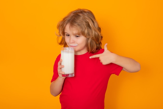 Child with a glass of milk on studio background Cute boy in white shirt holding glass of milk on isolated on yellow Portrait of kid with milk mustache