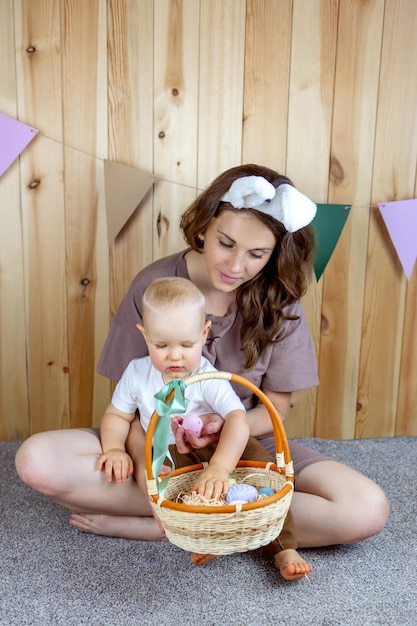 Child with mom in rabbit ears sit playing with Easter eggs Easter