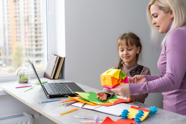 Child with mother have a fun cutting out scissors paper in preschool. mother and daughter make paper crafts