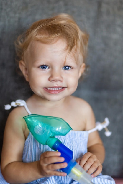 A child with snot holds a mask from a nebulizer in his hands