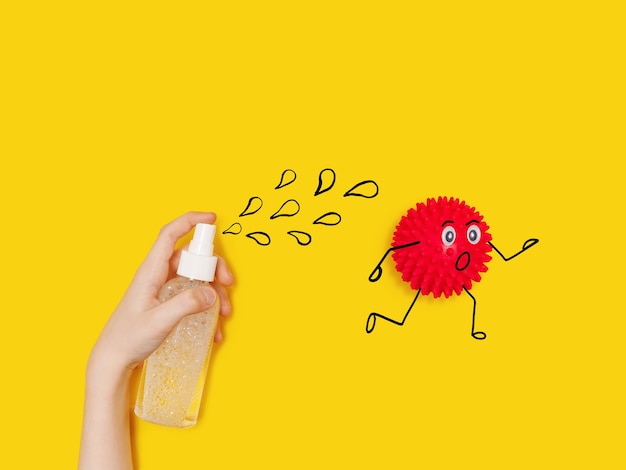 Child with  sprays with antiseptic to the cartoon coronavirus Covid-19 bacteria.