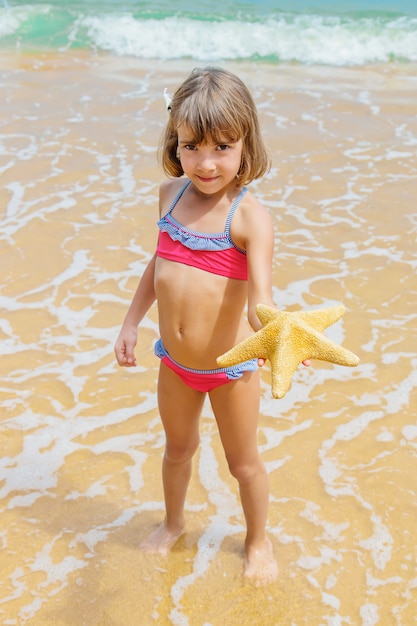 A child with a starfish in his hands on the beach