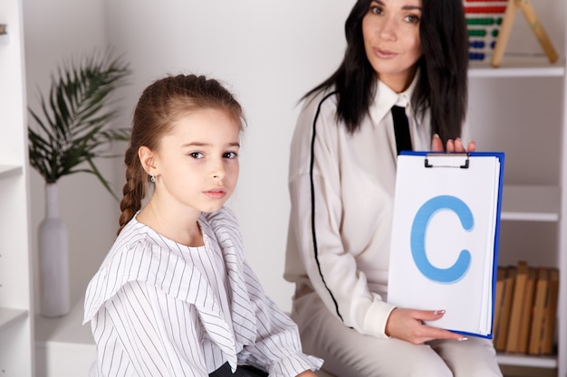 Child with therapist working on pronunciation and sounds together sitting in the class.